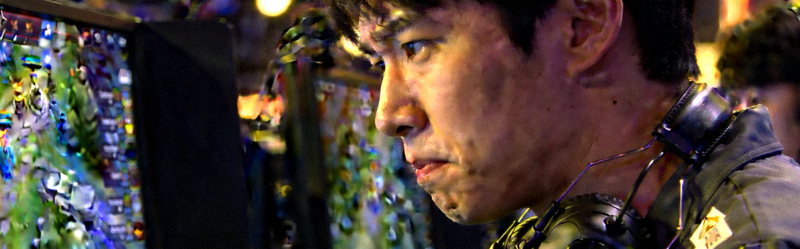 Faker李相赫选手在比赛中的专注侧脸特写，身后是比赛电脑